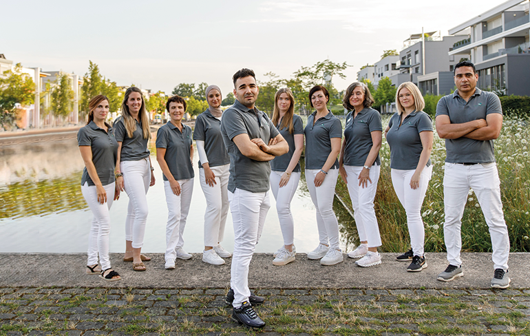 Team und der Inhaber der Petrisberg Apotheke in Trier stehen draußen auf einer Brücke für ein Gruppenfoto zusammen.