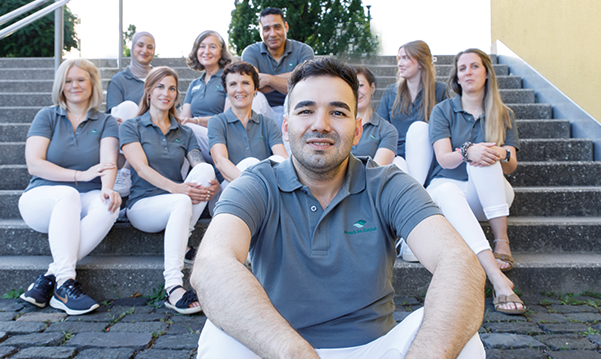 Das Apothekenteam sitz auf einer Treppe draußen zusammen, der Inhaber sitzt vorne, alle tragen ein Shirt der Petrisberg Apotheke.